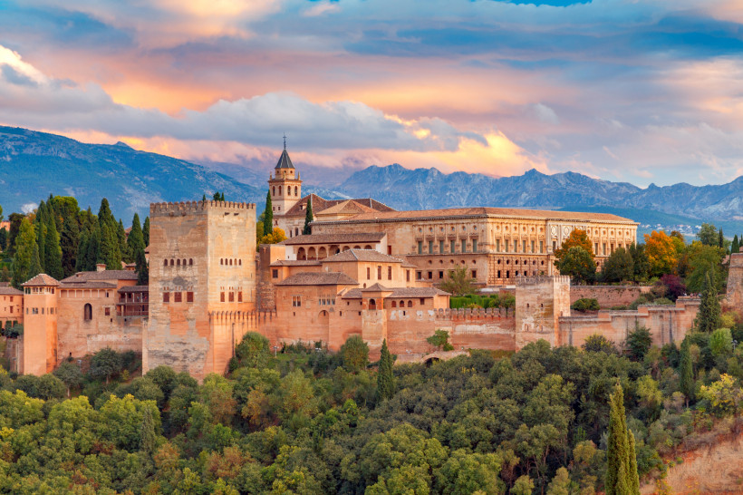 Blick auf die Alhambra in Granada mit Festungsmauern und Palastanlagen vor Bergkulisse bei Abendlicht