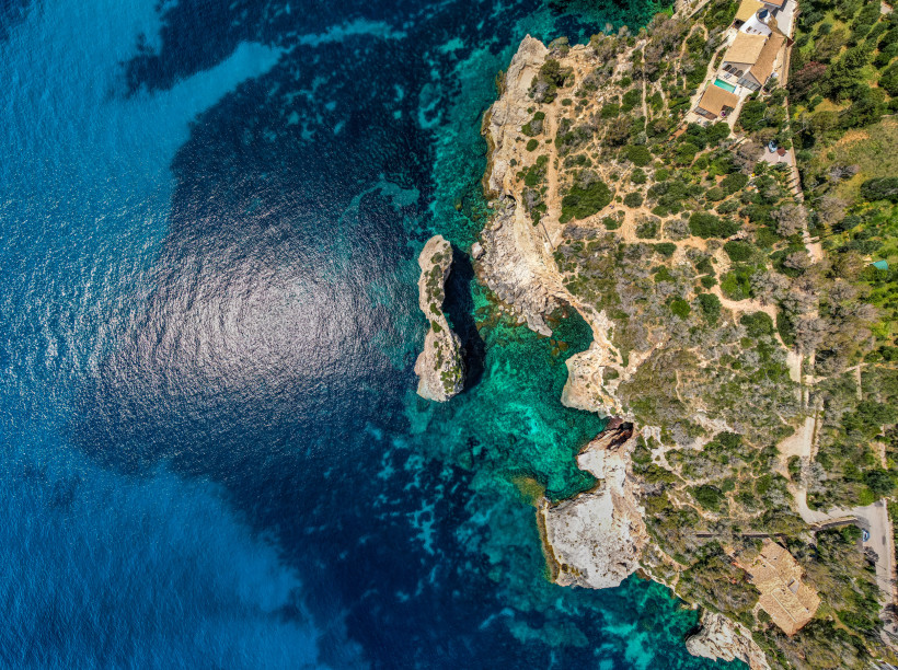 Cala d’Or, Mallorca Luftaufnahme der zerklüfteten Küste von Mallorca mit türkisblauem Meer, Felsen und einzelnen Häusern am Rand der Klippen
