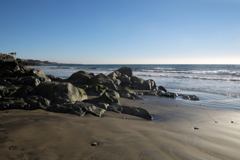 Felsige Küste an der Playa del Águila bei San Agustín mit Sandstrand und Wellen