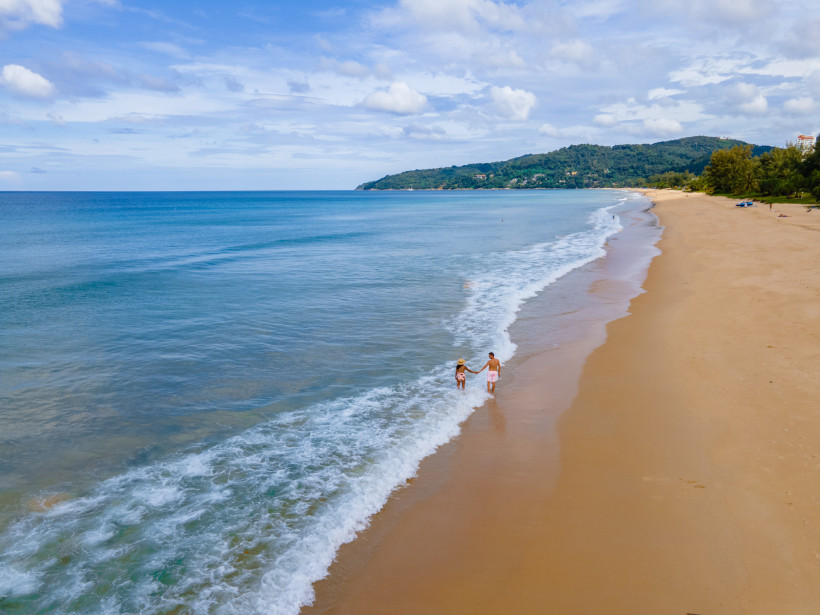 Karon Beach Phuket – Traumstrand für Paare und Erholung Paar spaziert Hand in Hand am Karon Beach auf Phuket entlang des feinen Sandstrandes mit türkisblauem Meer
