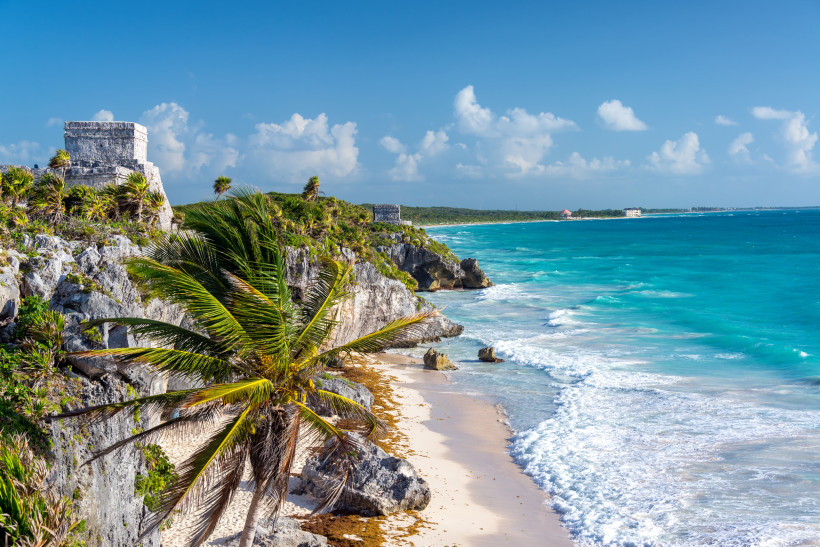 Mexiko, Frühling Küstenlandschaft von Tulum, Mexiko, mit Maya-Ruinen auf einer Klippe, türkisblauem Meer, weißem Sandstrand und üppigen Palmen