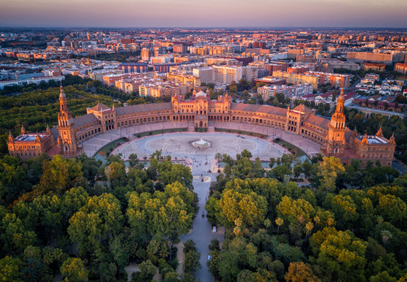 Luftaufnahme der Plaza de España in Sevilla mit halbkreisförmigem Gebäudekomplex, Platzanlage und Brunnen
