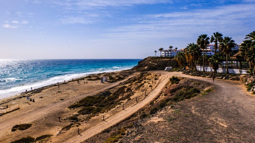 Küstenabschnitt der Playa de Esquinzo mit Strand, Meer und Häusern auf einer Felsklippe