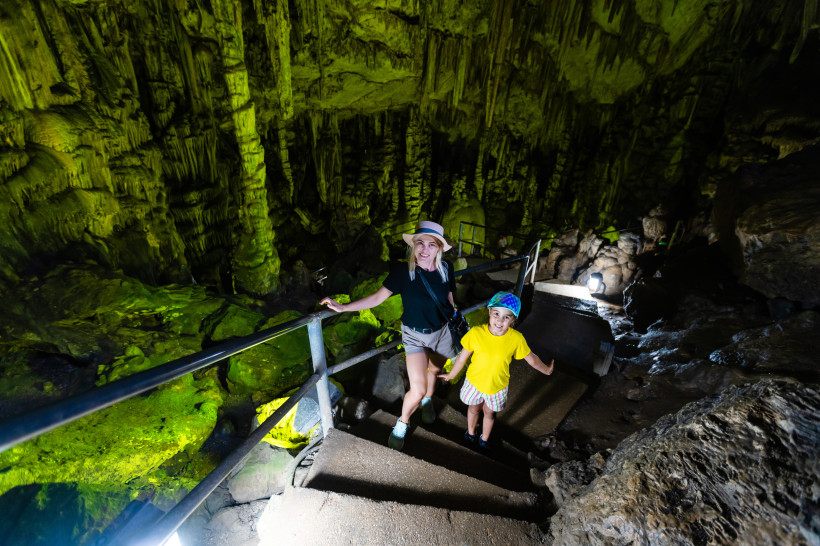 Treppe im Inneren der Zeus-Höhle mit beleuchteten Tropfsteinformationen und Geländer