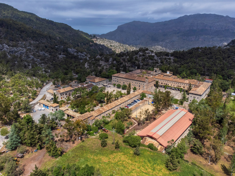 Mallorca - Kloster Lluc Luftaufnahme des Klosters Lluc in der Serra de Tramuntana auf Mallorca. Die Klosteranlage liegt eingebettet in eine grüne, bergige Landschaft. Die Gebäude bestehen aus sandfarbenem Stein mit roten Ziegeldächern und sind von schmalen Straßen und Wegen umge