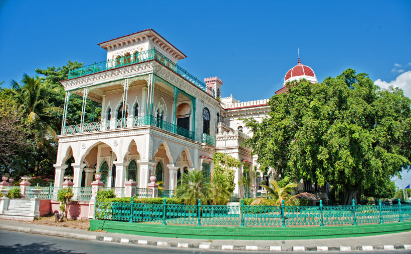Der prächtige Palacio de Valle in Cienfuegos auf Kuba mit maurisch inspirierten Bögen, filigranen Verzierungen, türkisfarbenen Balkonen und Gartenanlage unter blauem Himmel – ein Wahrzeichen der Stadt.