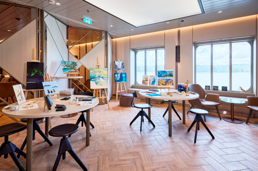 Atelier an Bord der Mein Schiff 7 mit Tischen, Staffeleien, Malutensilien und großen Fenstern