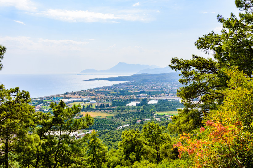 Blick über Çamyuva an der Türkischen Riviera mit grünen Pinienwäldern, Feldern, Küstenort und dem Mittelmeer im Hintergrund