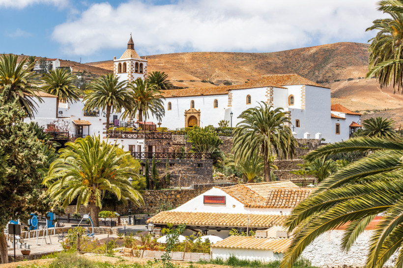 Kirche Santa María in Betancuria – Geschichte inmitten tropischer Gärten Betancuria Santa María Kirche – historische Sehenswürdigkeit Fuerteventura umgeben von Palmen und traditionellen Häusern