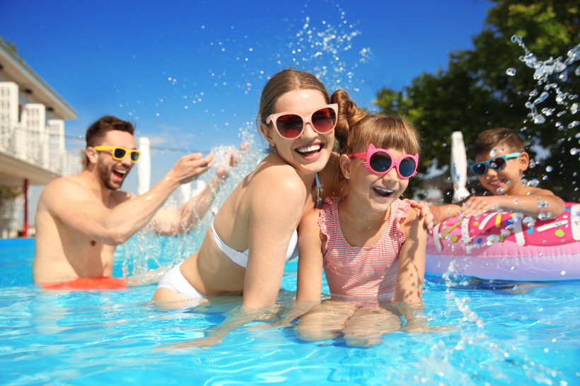 Fröhliche Familie mit Kindern beim Spielen im Pool eines familienfreundlichen Hotels – budgetfreundlicher Familienurlaub mit Wasserspaß, Entspannung und gemeinsamen Erlebnissen.