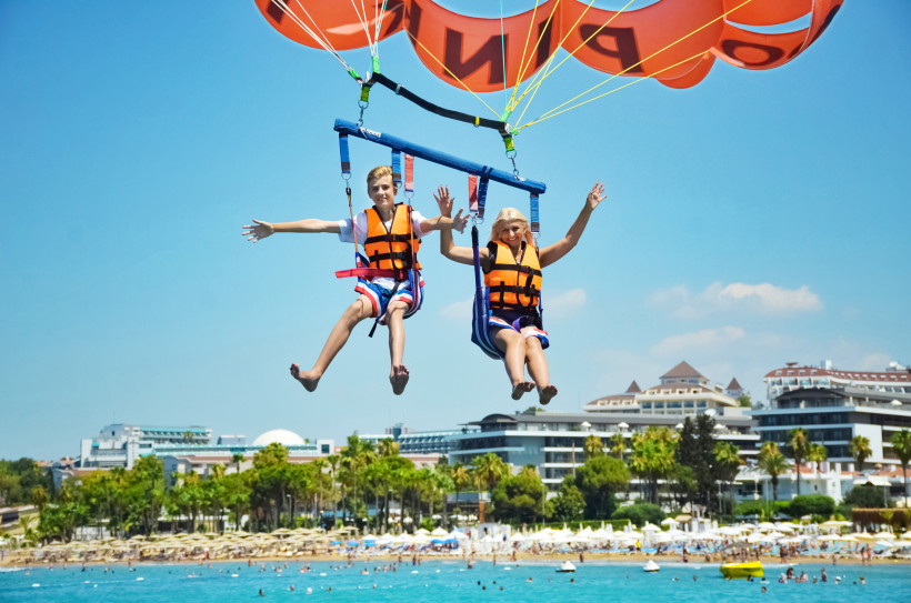 Familienurlaub in Belek – Parasailing und Wassersport an der Türkischen Riviera Mutter und Sohn beim Parasailing vor der Küste von Belek, beide mit Rettungswesten in der Luft schwebend – beliebtes Familienabenteuer im Türkeiurlaub