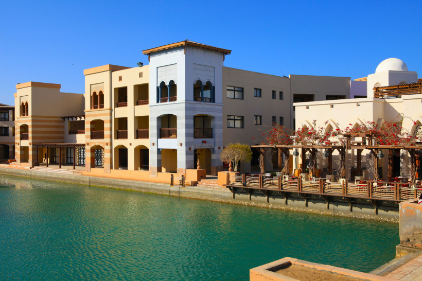Bunte Häuser und Uferpromenade am türkisblauen Wasser des Roten Meeres.