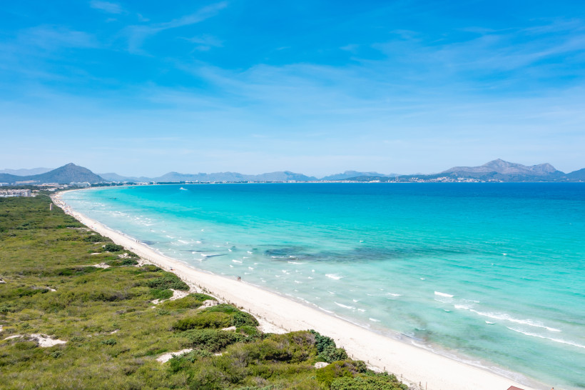 Mallorca - Playa de Muro Luftaufnahme der Playa de Muro an der Nordküste Mallorcas. Der lange, weiße Sandstrand erstreckt sich kilometerweit entlang des türkisblauen Meeres. Links im Bild grenzt der Strand an ein großes Naturschutzgebiet mit grünen Dünen und dichter Vegetation. A