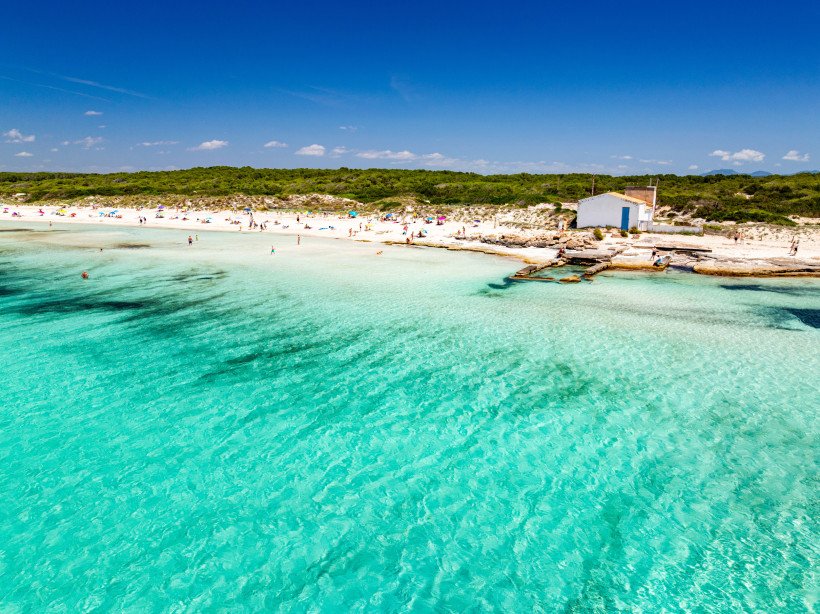 Es Trenc-Strand, Mallorca Menschen genießen den weißen Sandstrand und das kristallklare Wasser an einem sonnigen Tag auf Mallorca