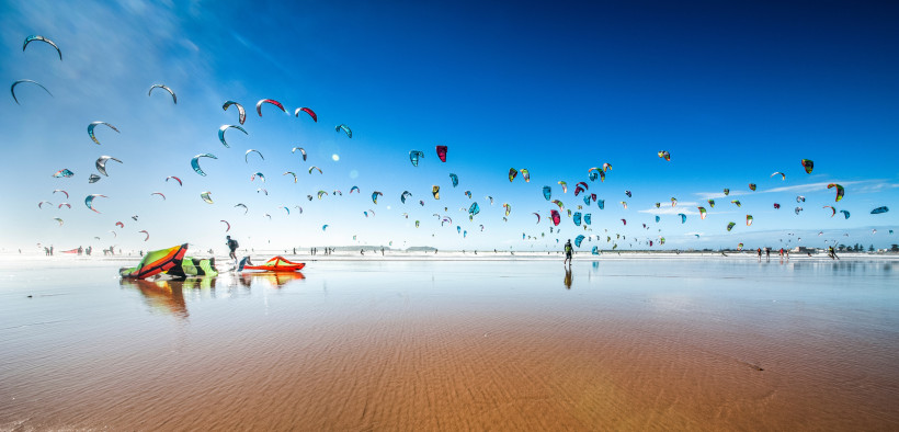 Essaouira – Paradies für Kitesurfer an Marokkos Atlantikküste Bunte Kiteschirme am Strand von Essaouira, Marokko – beliebtes Reiseziel für Kitesurfer und Wassersportler an der Atlantikküste.