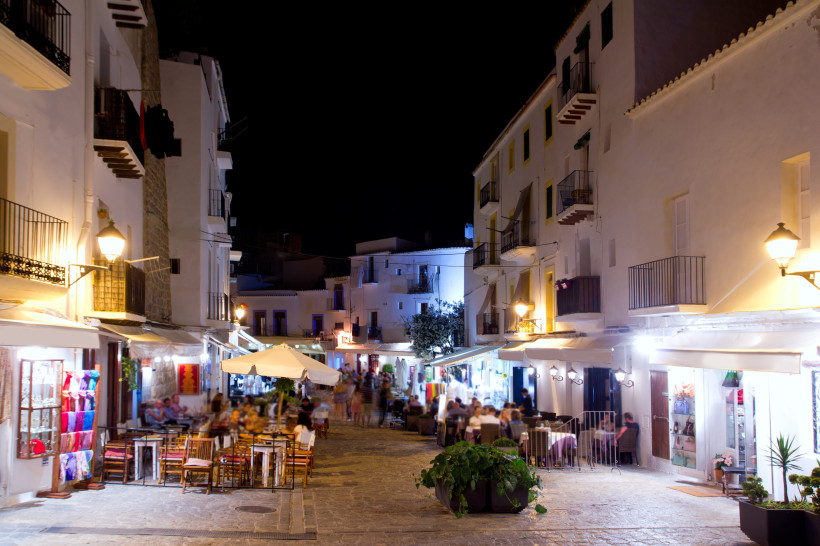 Abendliche Fußgängerzone in Dalt Vila mit weißen Häuserfassaden, Restaurants und Straßenlaternen