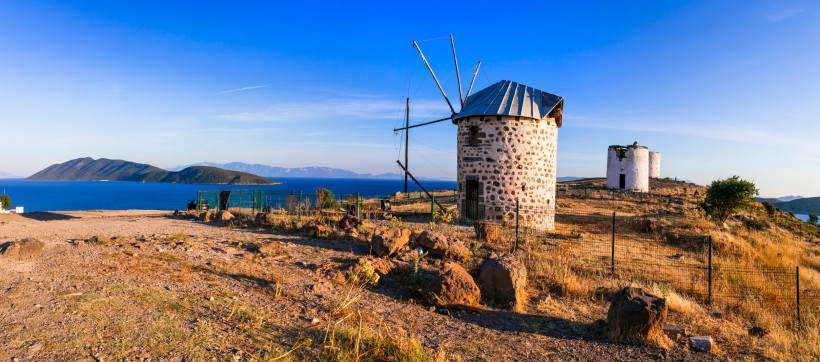 Historische Steinwindmühlen bei Bodrum auf einer Anhöhe mit Blick auf das tiefblaue Ägäische Meer