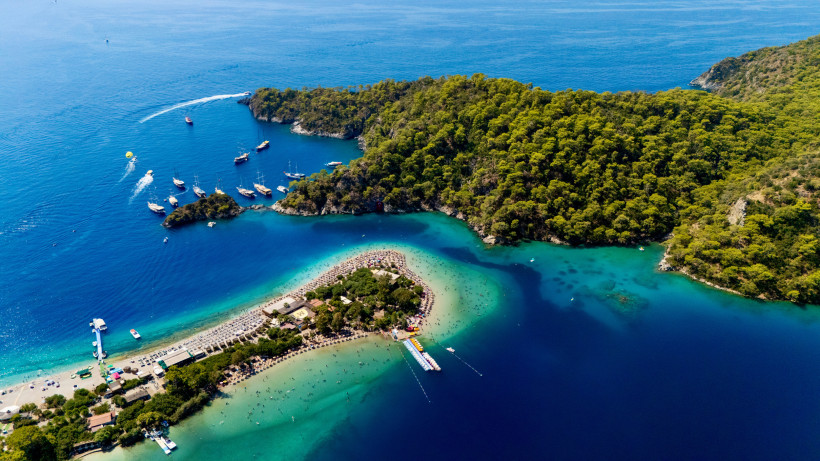 Luftaufnahme der Lagune von Ölüdeniz mit Sandbank, türkisfarbenem Wasser, Booten und bewaldeter Halbinsel