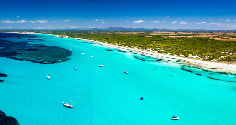 Luftaufnahme von Es Trenc mit türkisfarbenem Meer, Sandstrand und mehreren Segelbooten