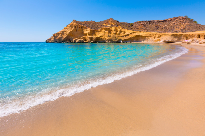 Sandstrand an der Playa de los Cocedores mit türkisblauem Meer und hellen Felsklippen