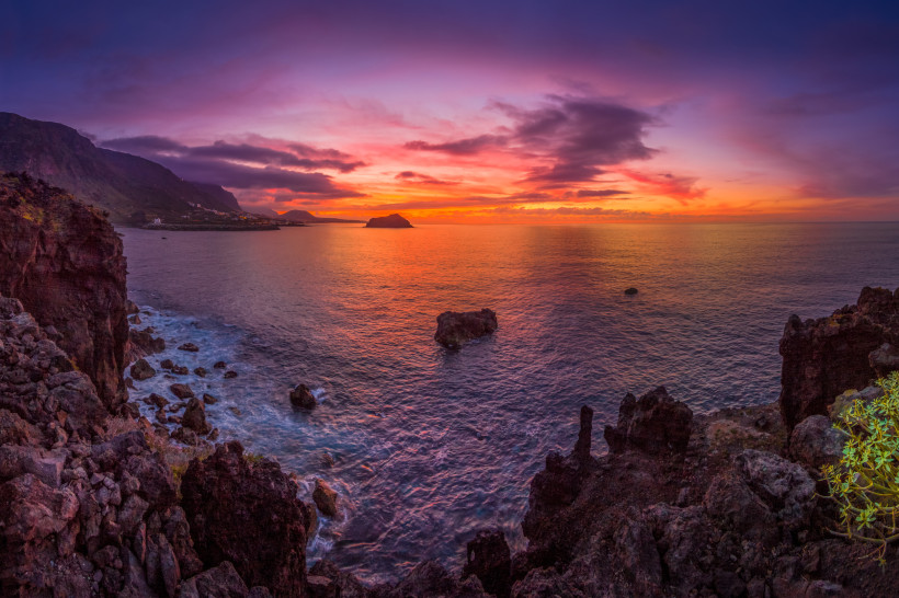 Felsenküste auf Teneriffa bei Sonnenuntergang mit orange-pinkem Himmel und ruhigem Meer