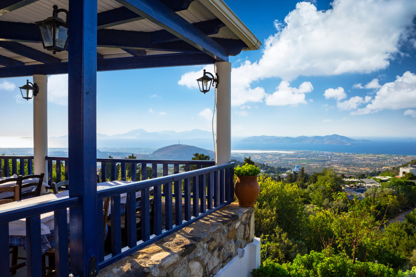 Kos - Zia Terrasse einer Taverne im Dorf Zia auf Kos mit blau-weißer Einrichtung und weitem Blick über die Insel bis zum Meer.