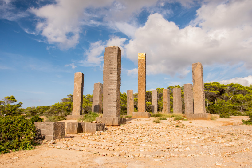 Solaruhr in Cala Llentia, Ibiza, mit Steinpfeilern unter blauem Himmel Solaruhr aus hohen Steinpfeilern in Cala Llentia auf Ibiza an einem Nachmittag