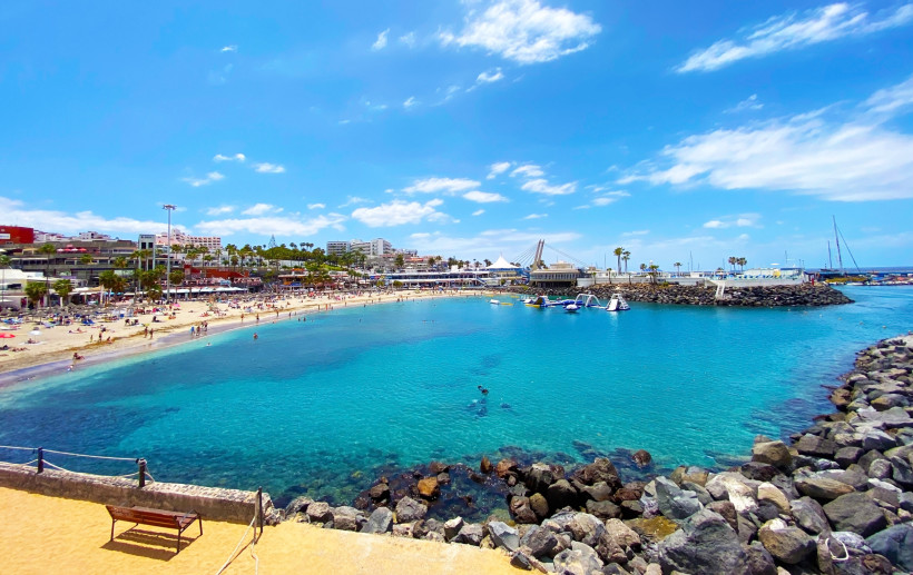 Puerto Colón – Strand und Hafenbecken mit Promenade Blick auf Puerto Colón mit Sandstrand, türkisfarbenem Wasser, Booten und Uferpromenade