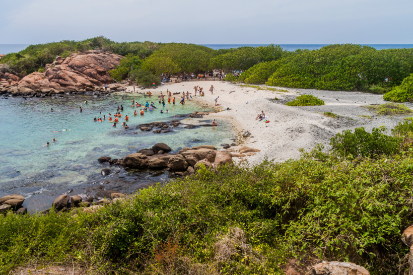 Trincomalee, Sri Lanka Badegäste am Strand und im klaren Wasser von Pigeon Island bei Trincomalee, Sri Lanka, umgeben von Felsen und Mangroven