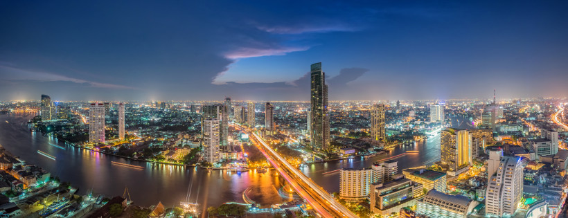 Panoramablick auf die nächtliche Skyline von Bangkok mit Hochhäusern und dem Chao-Phraya-Fluss