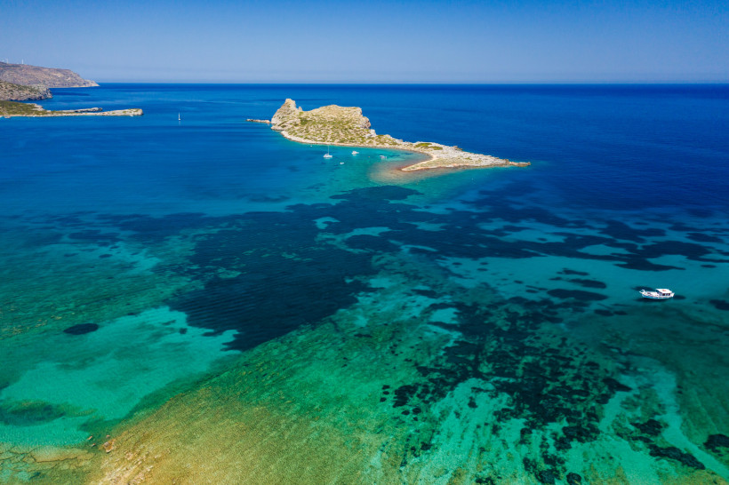Insel Kolokitha, Luftaufnahme mit flachem türkisfarbenem Wasser und Küstenlinie Luftaufnahme der Insel Kolokitha mit türkisfarbenem Meer und Booten