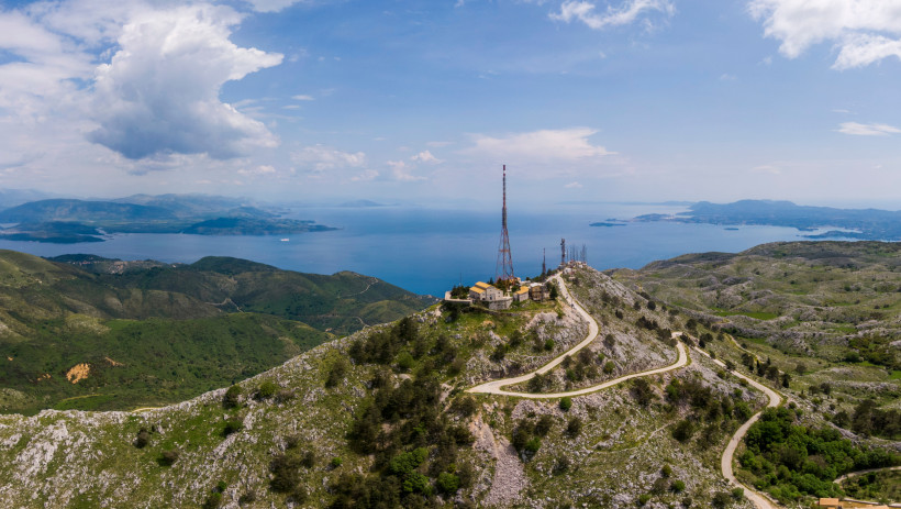 Blick vom Berg Pantokrator auf Korfu: kurvenreiche Straße, Funkmasten und Panoramablick auf das Meer und Nachbarinseln.