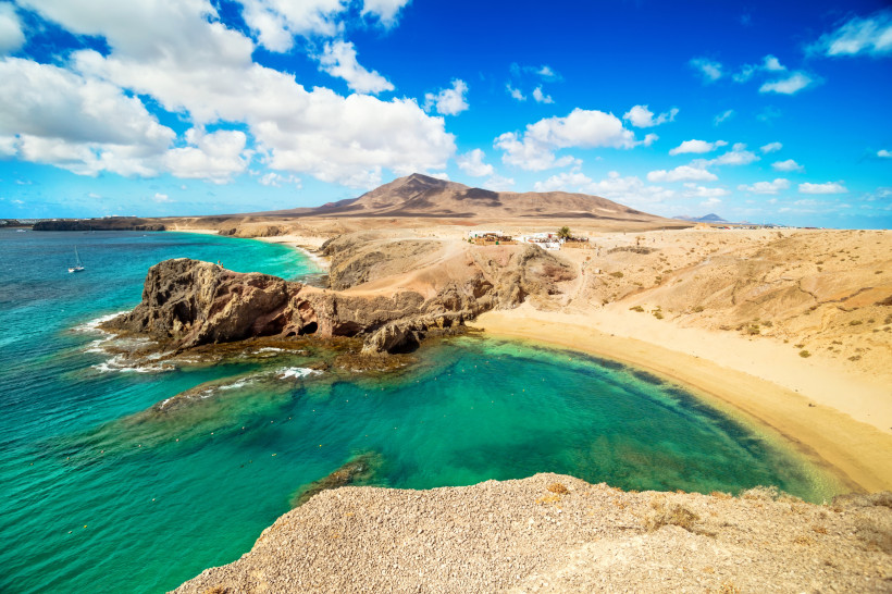 Aussicht auf die Playa de Papagayo – Lanzarotes schönster Naturstrand Goldener Sandstrand Playa de Papagayo mit kristallklarem türkisfarbenem Wasser und bizarren Felsformationen auf Lanzarote