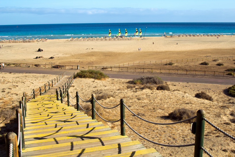 Aussichtsrampe am Playa Jandia mit Blick auf Meer und Dünen Holzsteg am Jandia Playa auf Fuerteventura mit Blick über Dünenlandschaft, Strand und türkisblaues Meer