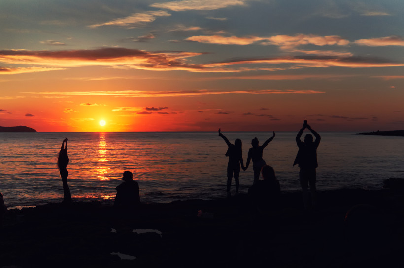 Sonnenuntergang über dem Meer bei Café del Mar, Silhouetten von Menschen am Ufer