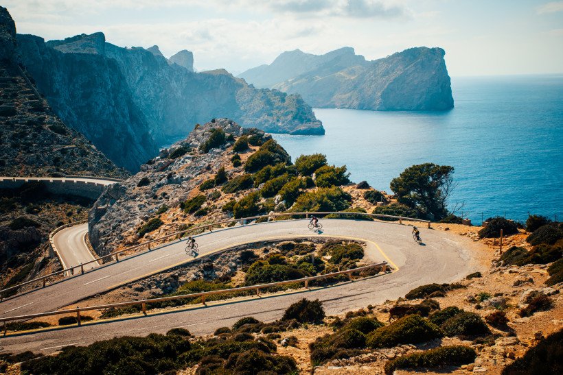Rennradfahrer auf Serpentinenstraße an der Küste bei Port de Pollença, Mallorca