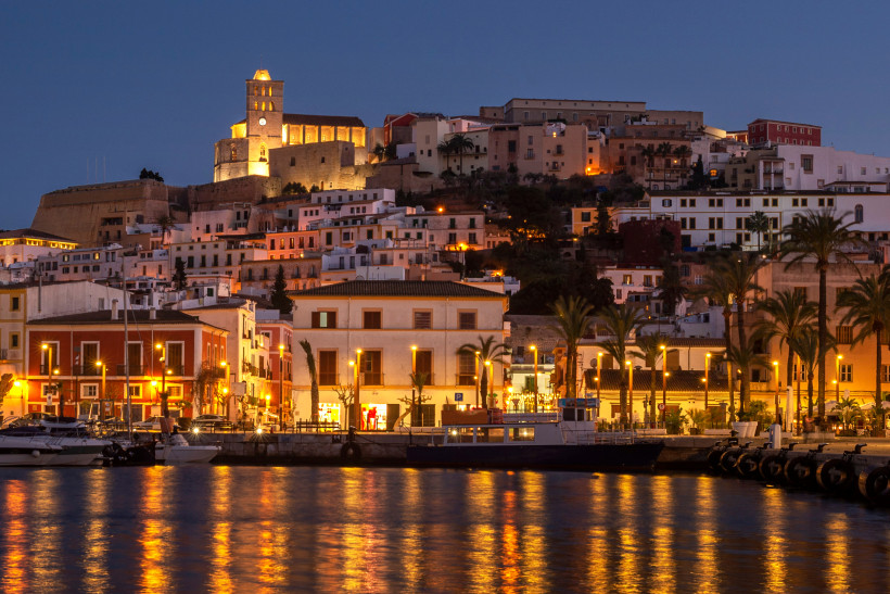 Abendansicht der Marina von Ibiza mit beleuchteter Altstadt und Kirche am Hang, Boote im Hafen