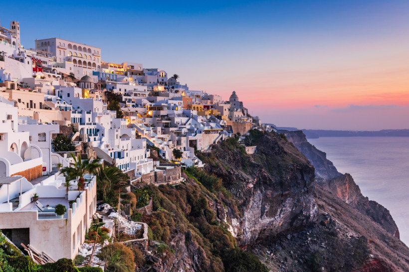 Santorini - Fira (Thira) Fira bei Sonnenuntergang: weiß getünchte Häuser kleben an der Kraterkante, rosa-blauer Himmel über der Ägäis