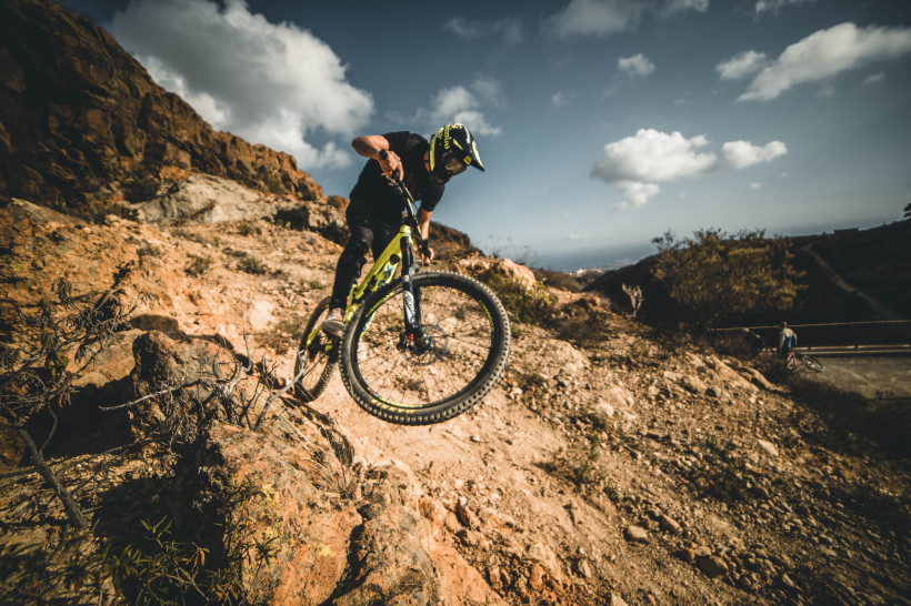 Mountainbiker auf anspruchsvoller Trail-Strecke auf Teneriffa Ein Mountainbiker springt über Felsen auf einem steinigen Trail in der bergigen Landschaft Teneriffas.
