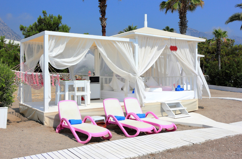 Luxuriöser Strandpavillon mit weißen Vorhängen und Sonnenliegen in einem exklusiven Resort in Kemer an der Türkischen Riviera