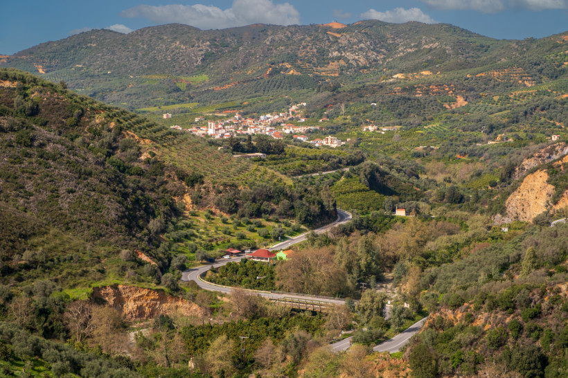 Westkreta: Dorf in den Bergen zwischen Olivenhainen und Serpentinenstraße Berglandschaft mit Olivenhainen und einem Dorf in Westkreta, kurvige Straße im Tal