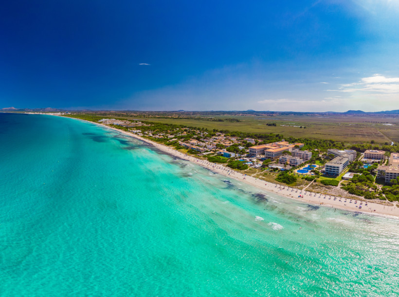 Luftaufnahme der Playa de Muro mit langem Sandstrand, türkisfarbenem Meer und Hotelanlage an der Küste
