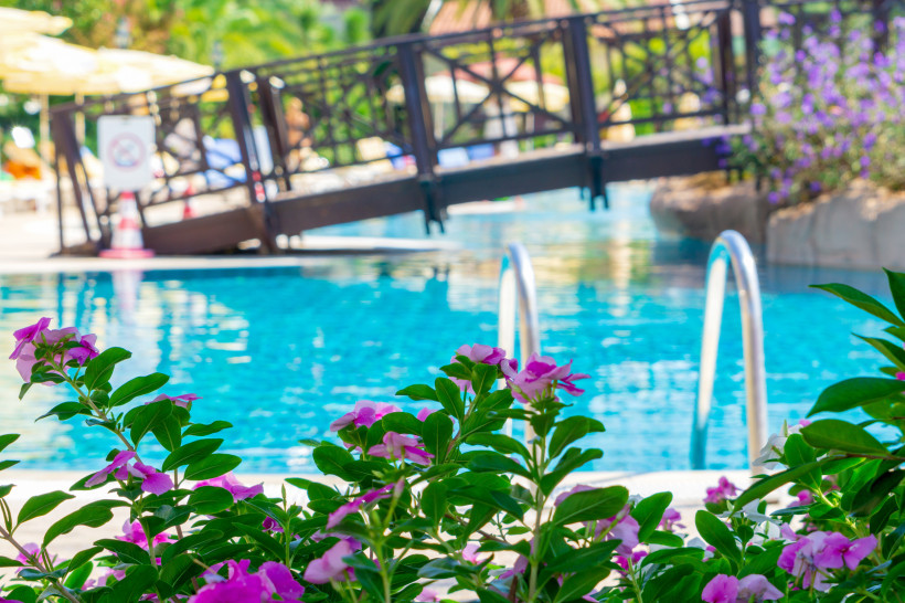 Poolanlage in einem Hotel in Kemer mit Blumen, Brücke und türkisblauem Wasser – perfekter Urlaub in der Türkei mit sehr gutem Preis-Leistungs-Verhältnis