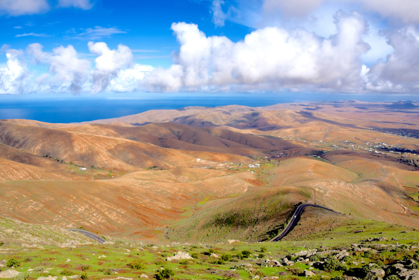 Frühling auf Fuerteventura – Natur erleben und milde Temperaturen genießen Blick über die grünen Hügel Fuerteventuras im Frühling mit blauem Himmel und vereinzelten Wolken – ideales Wetter für Wanderungen und Ausflüge.