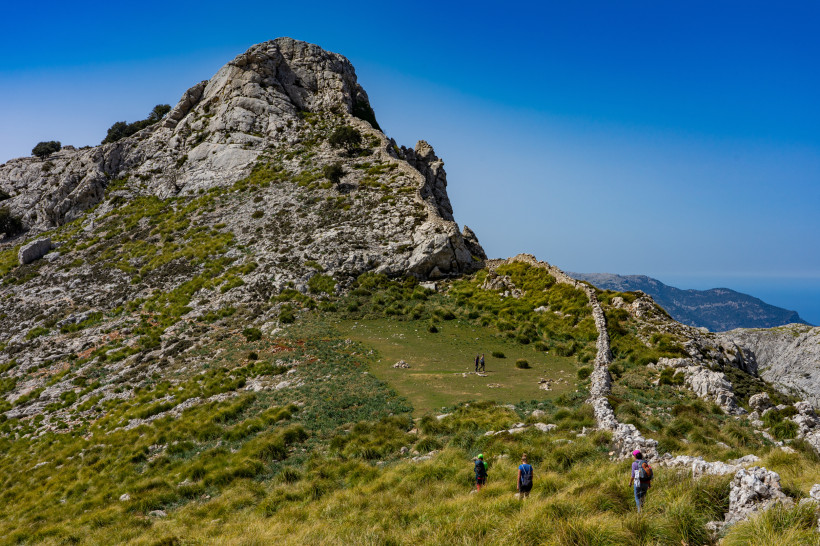Wanderpfad in der Serra de Tramuntana mit Bergkuppe, Trockensteinmauer und Wanderern