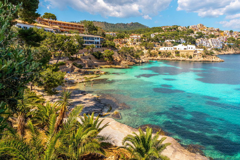 Cala Fornells mit türkisfarbenem Wasser, Felsplateaus, Pinien und Hotels oberhalb der Bucht