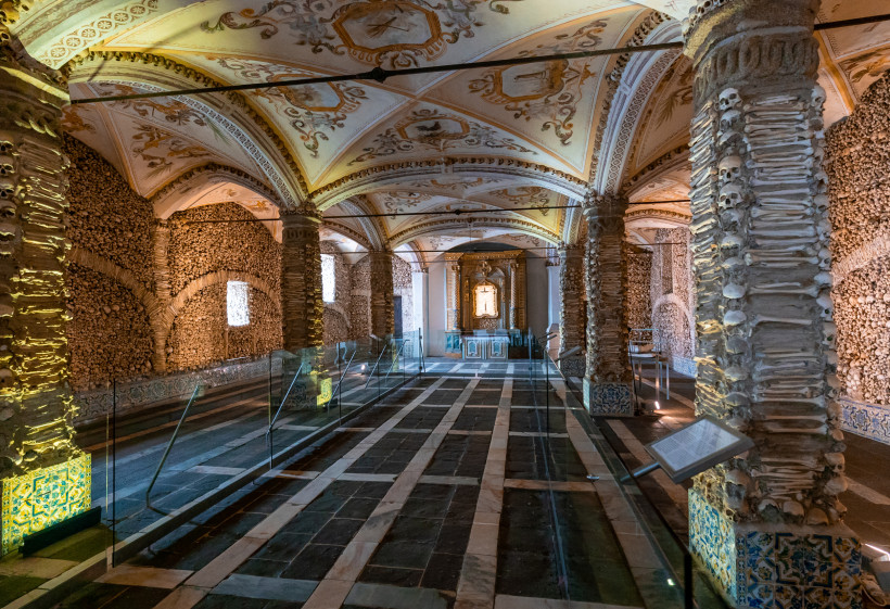 Innenraum der Knochenkapelle (Capela dos Ossos) in der Kirche São Francisco, Évora, mit Gewölbedecke und mit Knochen verkleideten Säulen und Wänden