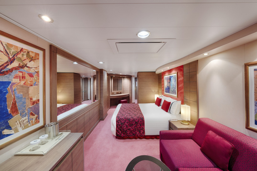 Schlafbereich der Premium Suite Aurea (SL1) auf der MSC Orchestra mit Doppelbett, Sofa und Spiegelwand
