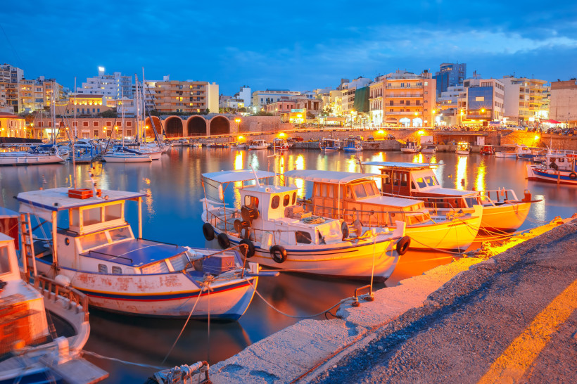 Boote im Hafen von Heraklion bei Dämmerung, Stadtkulisse im Hintergrund
