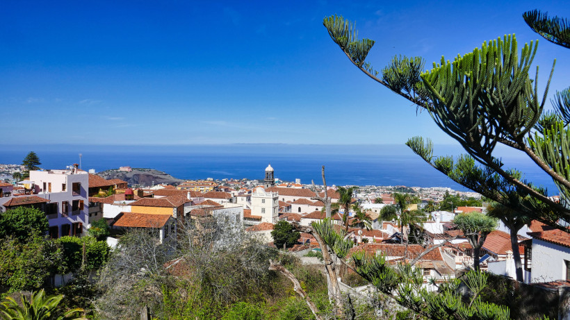 Blick über La Orotava auf Teneriffa mit roten Ziegeldächern, Kirchturm und Atlantik im Hintergrund